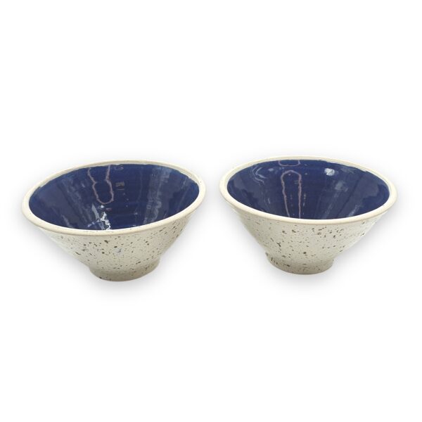 Two Leafbud Pearl wok bowls with speckled white exteriors and deep blue interiors
